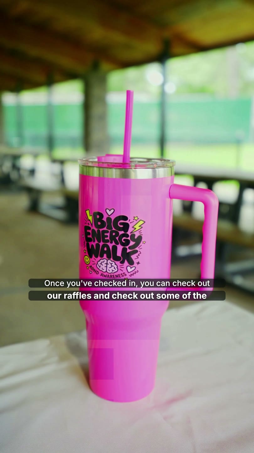 Pink Big Energy Walk tumbler on a table under the park pavilion, a raffle prize from the promo video