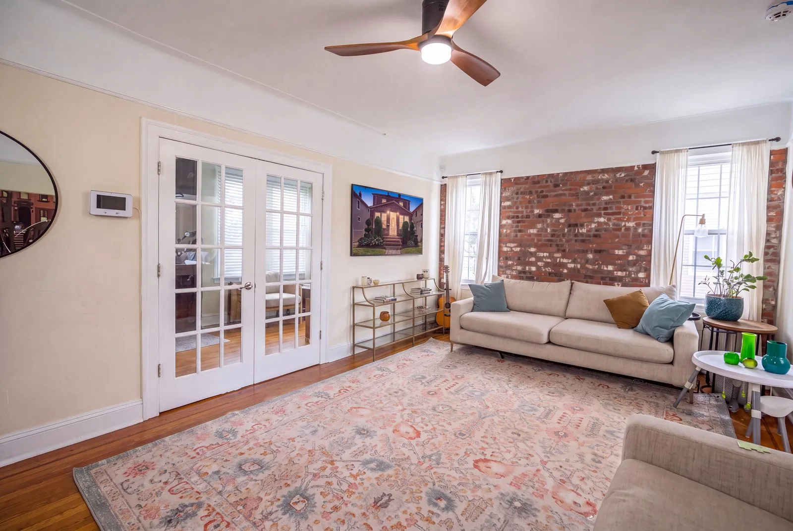 Living room with an exposed brick wall and French doors, real estate interior photography, Queens