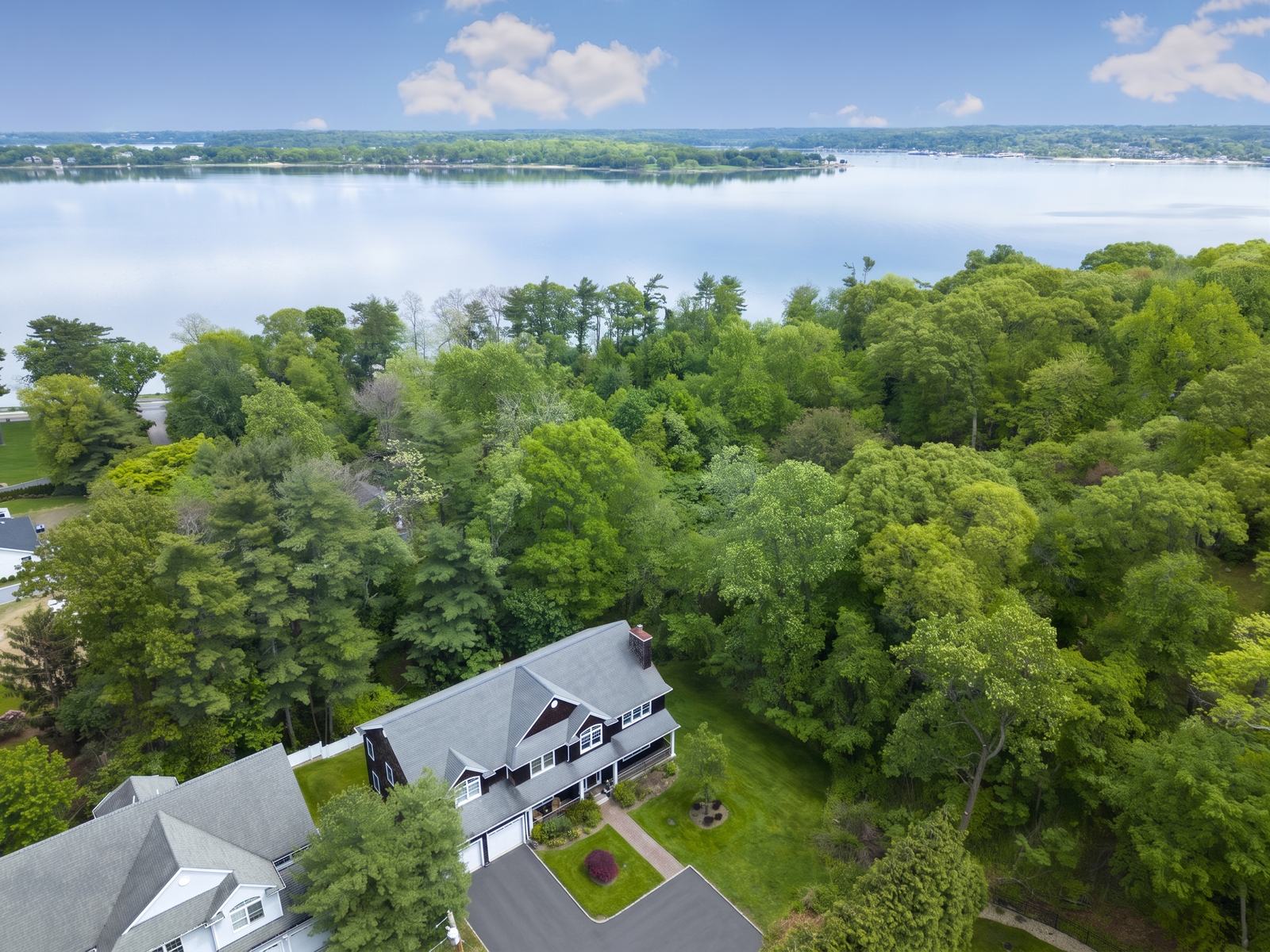 Aerial view over wooded homes toward the harbor, listing photography, Nassau County